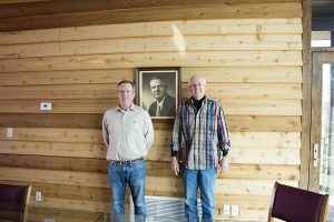 Robbie and Rob Erlbacher, with portrait of founder Robert Erlbacher.