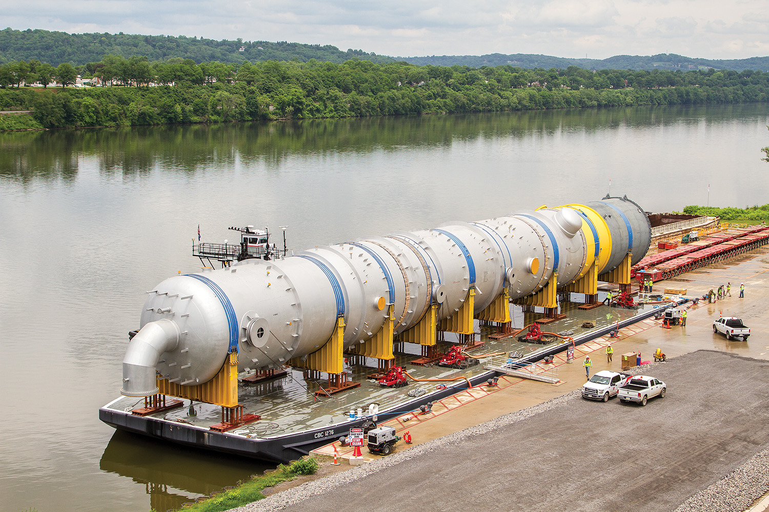 The mv. Big Eddie of Crosby Marine is seen at Monaca, Pa., Mile 27.9 of the Ohio River, on May 30 with a deck barge carrying a large refiner vessel for the Shell Oil Corporation ethylene cracker plant under construction. The picture shows the pumps used to level the barge for unloading, and the heavy-duty flatbed carrier to transport the equipment to the construction site. (Photo by Eric M. Johnson)
