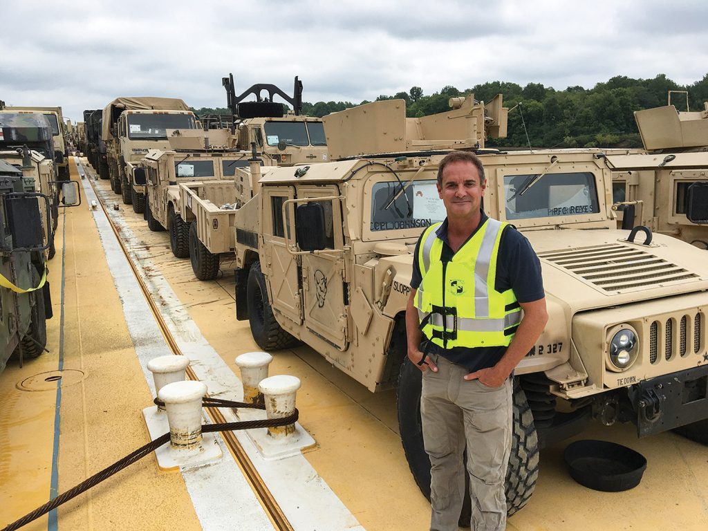 Dan Frankum, president of Glenn E. Daulton Inc., poses onboard one of 45 deck barges loaded with military equipment and vehicles. (Photo courtesy of Glenn E. Daulton Inc.)