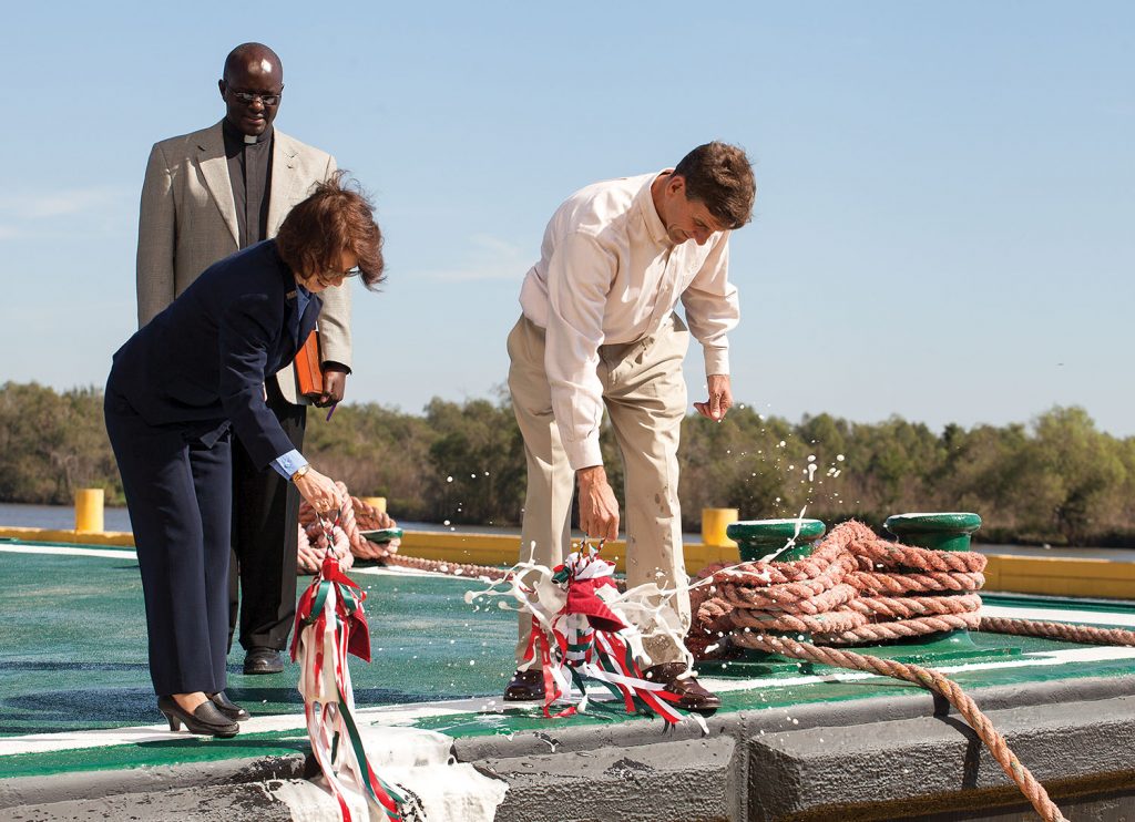 Harder and Smith christem barge while Rev. Engurait looks on. (Photo by Frank McCormack)