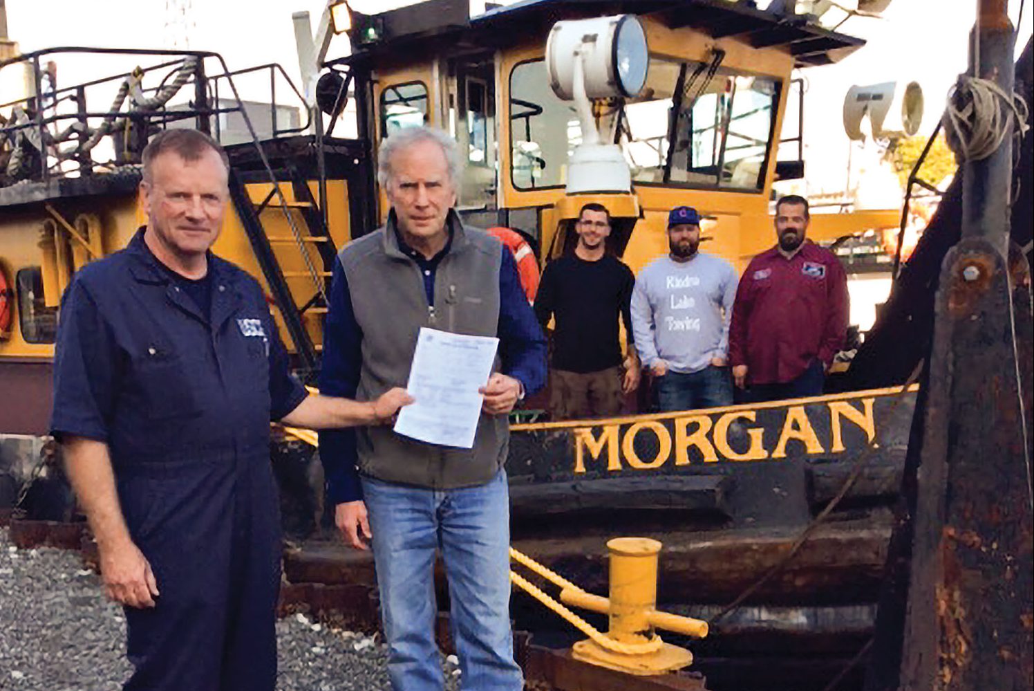 Jeff Carie, Marine Safety Unit-Chicago, presents John Kindra, president of Kindra Lake Towing LP, with its first Certificate of Inspection for the mv. Morgan as the vessel’s crew looks on. Crew members include Nijaz Jahovic, deckhand; Capt. Mike Hunter; and Ken Horn, deck engineer. (Photo courtesy of Kindra Lake Towing)