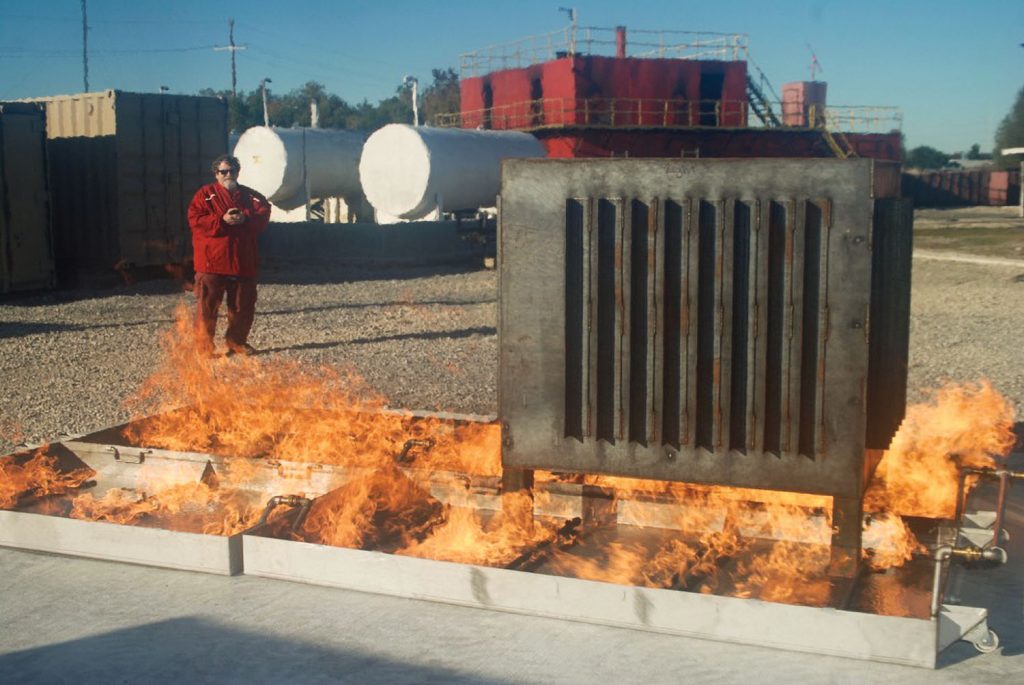 Ricky Heyd, fire school coordinator, demonstrating remote control ignition of two of the four new “props” on the school’s fire field. 