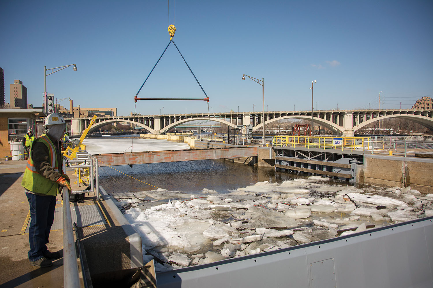 A contractor crews lifts steel bulkheads on the upstream side of the St. Anthony Falls Lock on March 20, a tricky maneuver completed in advance of anticipated high flows resulting from snowpack melt in the Mississippi headwaters. (Corps of Engineers photo by Patrick Loch)