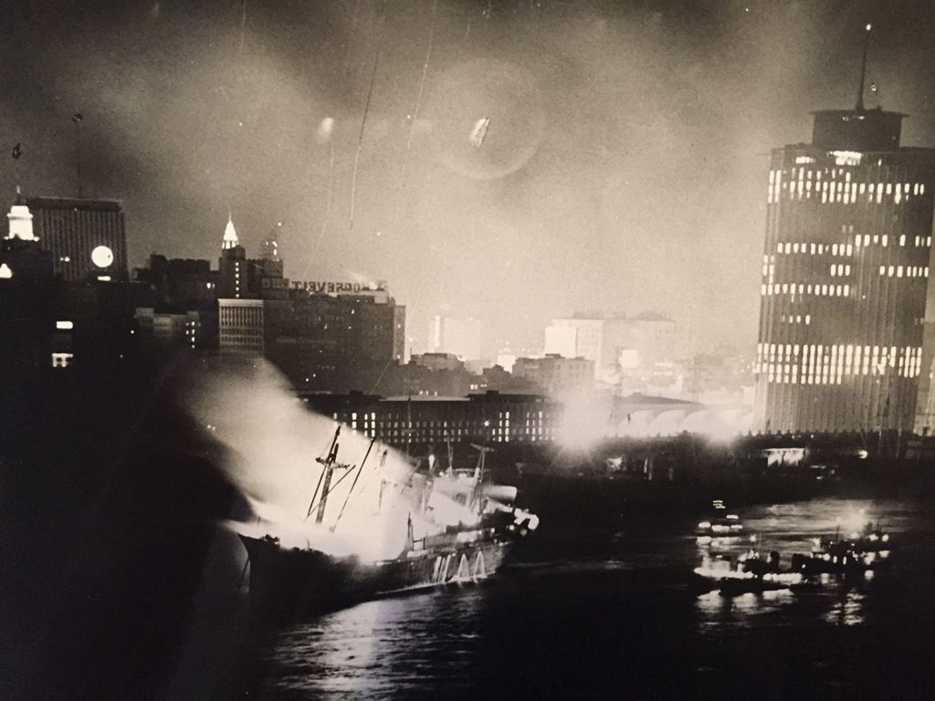 The Union Faith burning in the Mississippi River at New Orleans. The tall building was the ITM Building, now known as the World Trade Center.