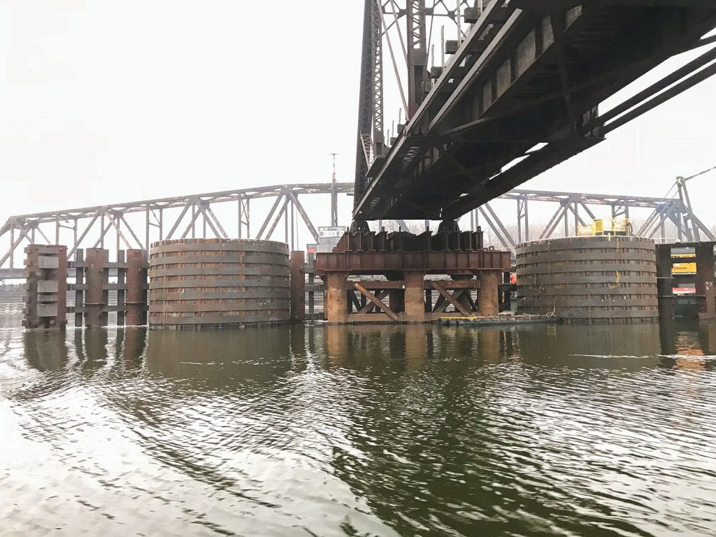 A back view of the new pier shows the elements of the structure, designed to withstand a collision by a fully loaded tow of barges. The pier is flanked by two 25-foot-diameter dolphins, each filled with 850 tons of limestone rock and capped by a five-foot-thick reinforced concrete slab. Eight steel bands were welded around each dolphin. (Photo courtesy of J.F. Brennan Company Inc.)