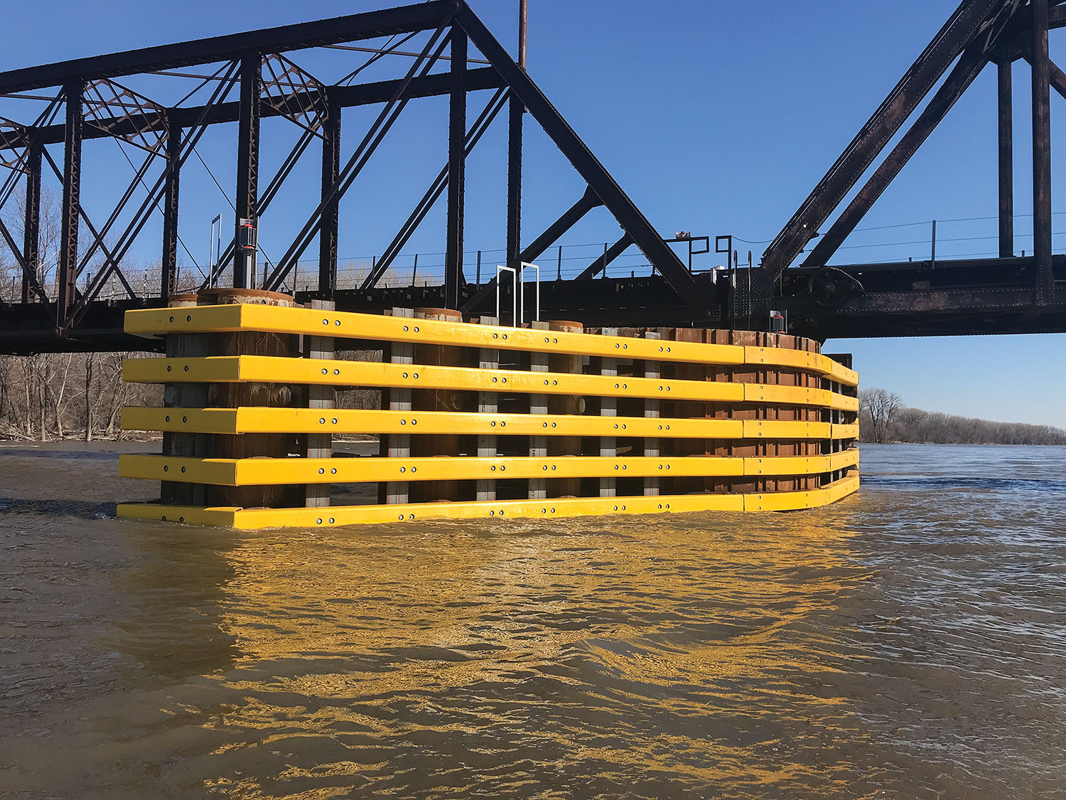 Yellow composite timber forms a 160-foot-long guide fence to deflect barges from the new center pier of the Union Pacific swing bridge at the south end of the Port of St. Paul. (Photo courtesy of J.F. Brennan Company Inc.)