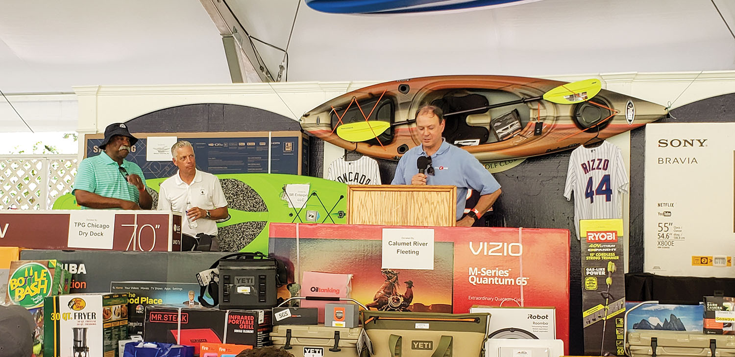 The Illinois River Association held its 39th annual meeting and golf outing July 10 in Lemont, Ill. During the awards ceremony, the association surprised Del Wilkins, left, with a lifetime achievement award, only the third such award in the association’s history. Canal Barge President Merritt Lane, at the microphone, describes Wilkins’ career while Sean Gerrity, chief operating officer of Midwest Tankermen and president of the organization, looks on. (Photo by Cheryl Eurick)