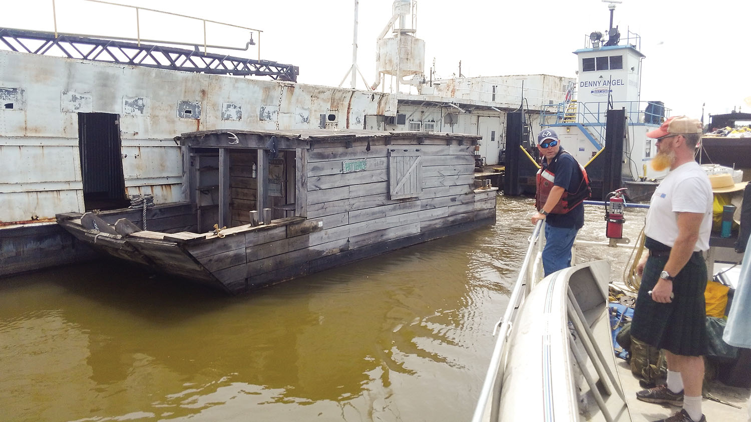 The replica flatboat Patience moored at the Economy Boat docks in Wood River, Ill.; a member of boat-builder Scott Mandrell’s crew looks on. (Photo courtesy of Scott Mandrell)