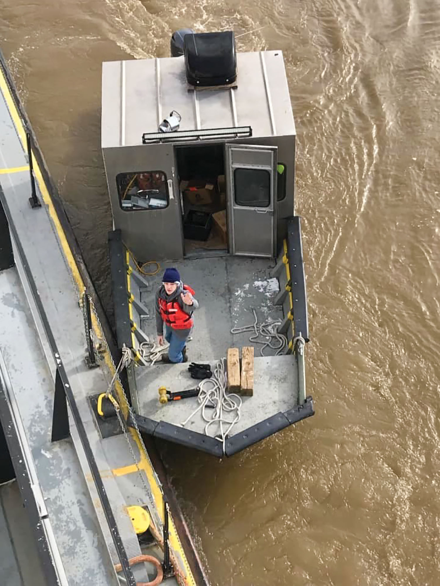 Larry Barnes’ son, John, waves from the deck of the smaller of the two vessels Barnes Marine uses to deliver supplies to towboats on the Ohio, Lower Cumberland, Lower Tennessee and Mississippi rivers. (Photo by Capt. Larry Barnes)