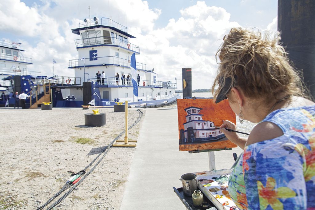 Stacey Rhoades, wife of the Rev. Thomas Rhoades, adds an artistic touch to the festivities by painting the mv. Ed S. (Photo by Frank McCormack)