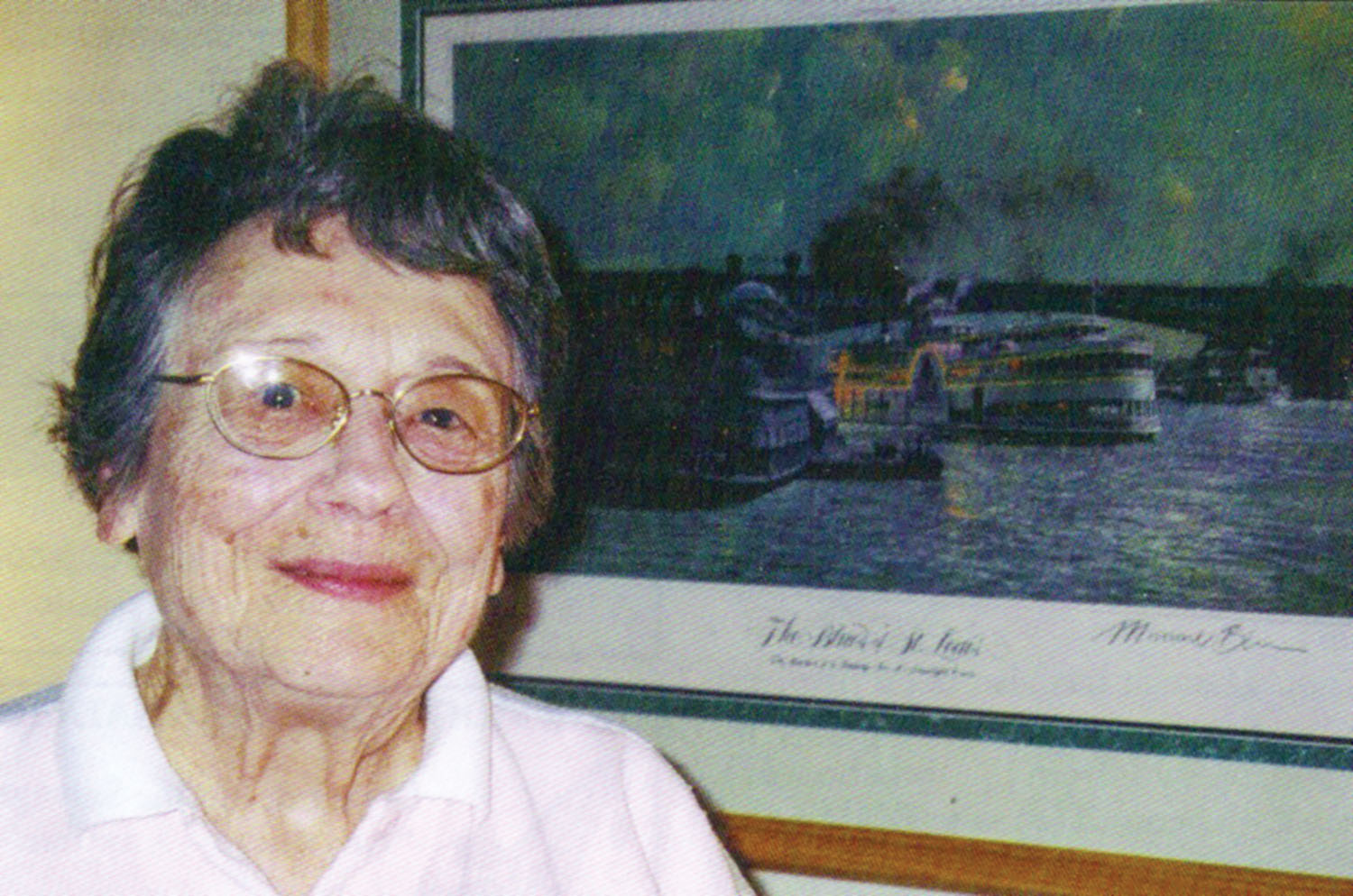 Mary Otte posing with Michael Blaser’s artwork, “The Blues of St. Louis,” featuring the Streckfus steamers Capitol and J.S. De Luxe, upon both of which Otte served as a crew member. (Photo by Judy Patsch)