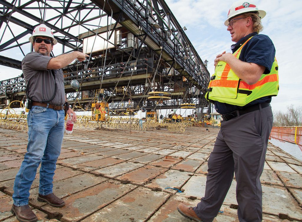 Mat Sinking Unit Chief Barry Sullivan (left) and John Cross, project manager for ARMOR 1, the next generation Mat Sinking Unit, stand aboard the current unit’s mat laying barge January 14. (Photo by Frank McCormack)