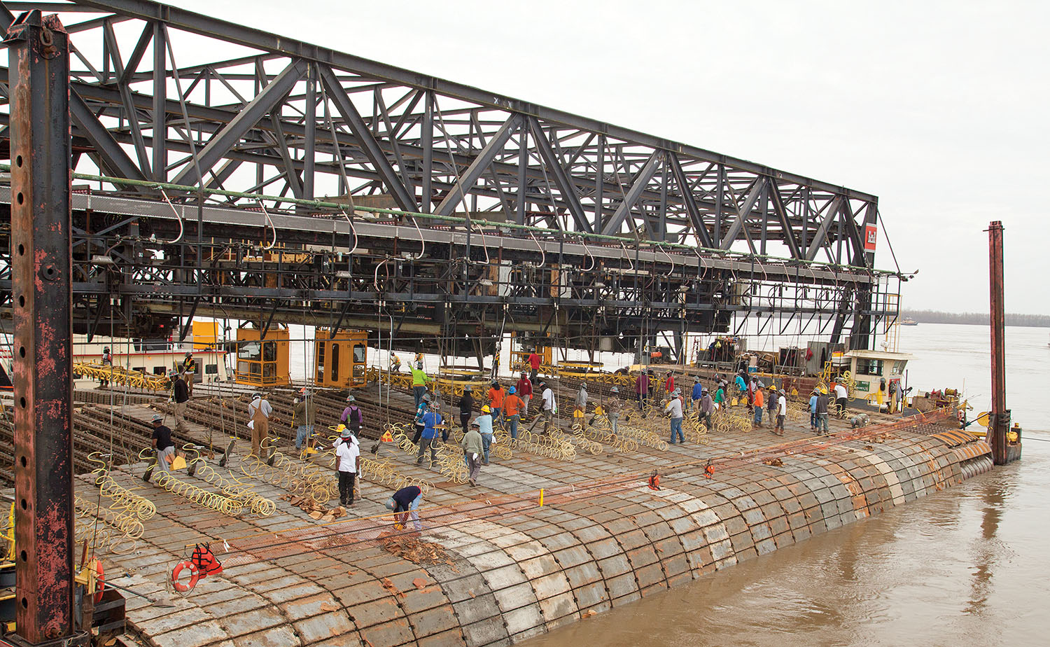 MSU crew members transfer concrete squares from a deck barge onto the mat laying barge. Each deck barge holds about 500 squares, and the MSU crew can lay six or seven barges’ worth of squares per day. (Photo by Frank McCormack)