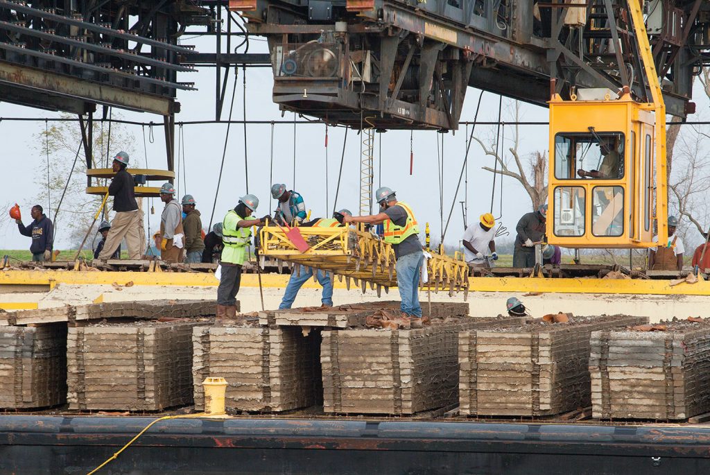 MSU crew members transfer concrete squares from a deck barge onto the mat laying barge. (Photo by Frank McCormack)