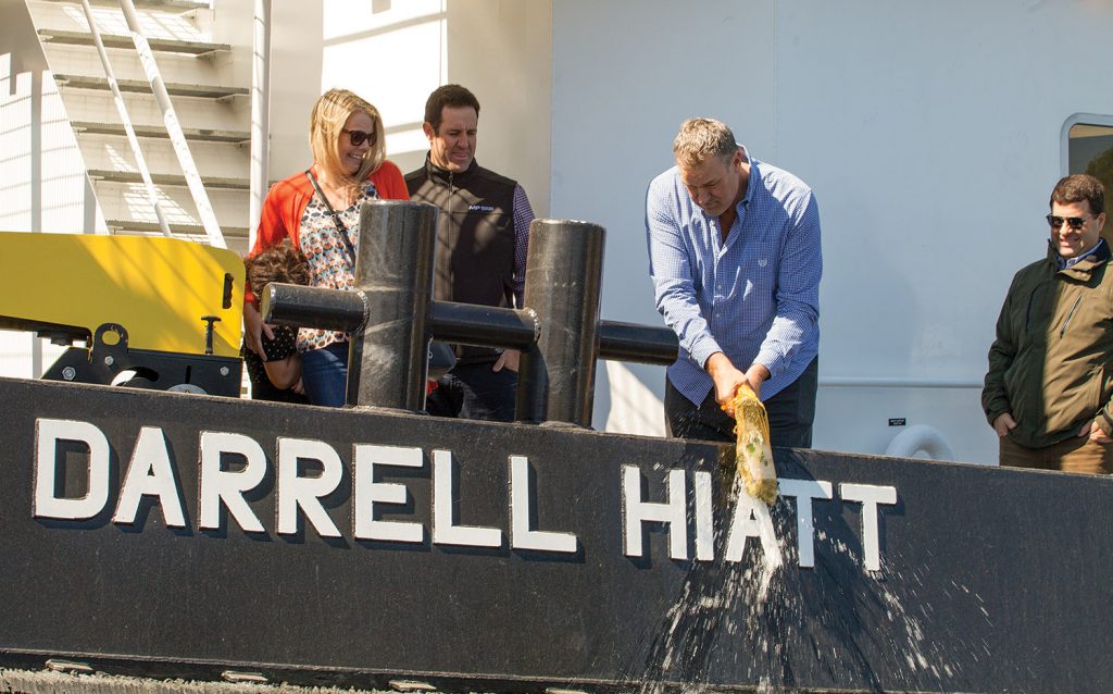 Darrell Hiatt christens the Maritime Partners vessel bearing his name. Looking on are Bubba Steiner (right), owner and operator of Steiner Construction; Karen Hiatt, Darrell's wife; and Austin Sperry, co-founder and chief operations officer of Maritime Partners. (Photo by Frank McCormack)