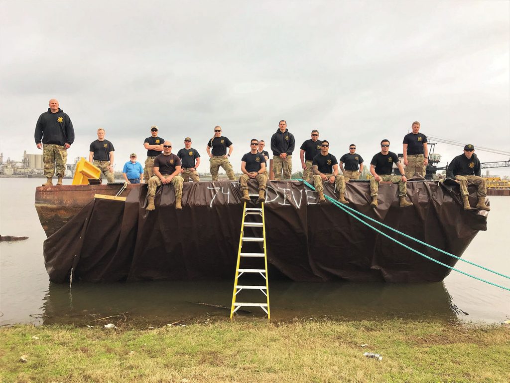 The 74th Army Dive Detachment Team sits atop the barge they successfully removed from the Ensley Engineer Yard stringout. Pictured left to right in the front row are 1st Sgt. Donald Lester, master diver; Staff Sgt. Richard Lee, dive supervisor; Staff Sgt. Trevin Currey, dive supervisor and noncommissioned officer in charge; Sgt. Alex Fanning, salvage diver, Spc. Nolan Hurrish, 2nd class diver; and Sgt. Michael Brown, salvage diver. Pictured left to right in the second row are 1st Lt. Christopher Thompson, diving officer and officer in charge; Sgt. Daniel Sivori, salvage diver; Sgt. Samantha Howleger, medic; and Pfc. James Lews, 2nd class diver. Pictured left to right in the third row are Sgt. Joshua Staats, salvage diver and Staff Sgt. David Corrales, salvage diver. Pictured left to right in the last row are Marine Facilities and Equipment Specialist Chad Chrisco, Pvt. Brady Harris, mechanic; and Spc. Pierce Castro, salvage diver. (Photo courtesy of the Memphis Engineer District)