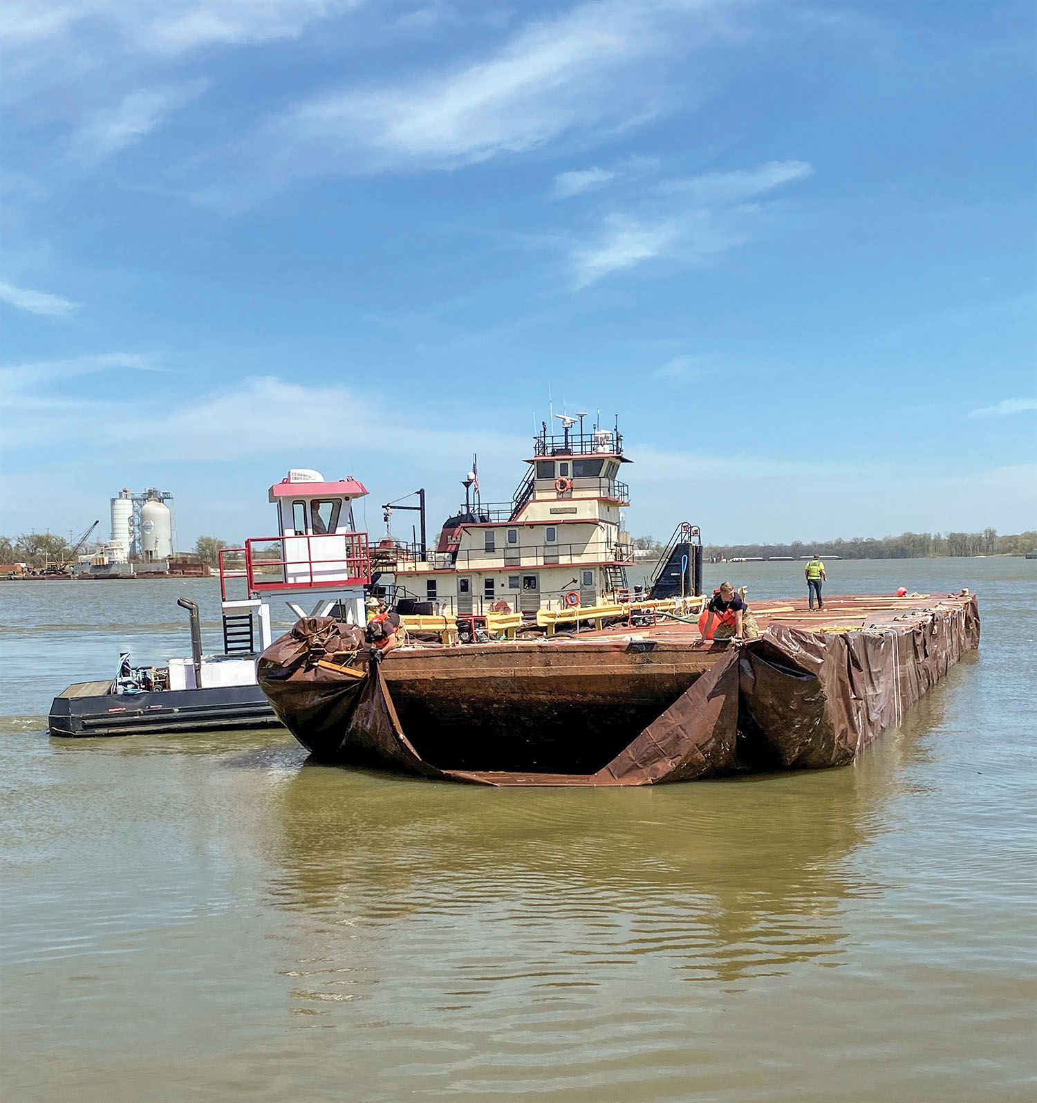 The mv. Goodwin and Ensley Engineer Yard’s truckable towboat remove the barge from the stringout and reposition it for transit to the west bank of the engineer yard for disposal while Army divers attach the front edge of the tarp for transit. (Photo courtesy of the Memphis Engineer District)