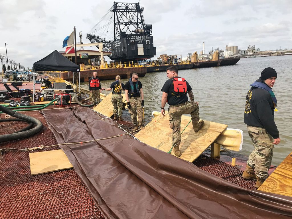 Members of the 74th Army Dive Detachment Team prepare to deploy one of the three tarps used to stabilize and remove the barge from the stringout. (Photo courtesy of the Memphis Engineer District)