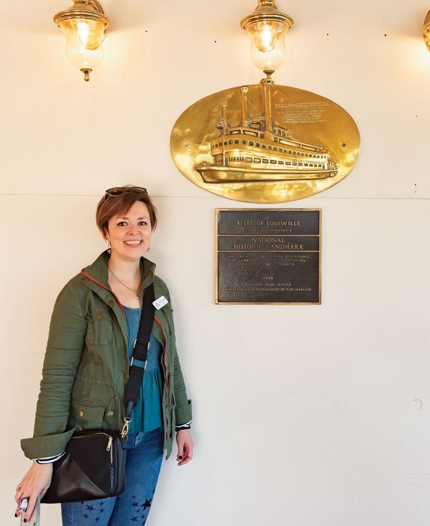 Belle of Louisville Riverboats CEO Krista Snider stands next to the Belle’s national historic landmark plaque. Snider started with the organization in August 2019, tasked with making it more sustainable and relevant to new audiences. (Photo by Kristen Warning)