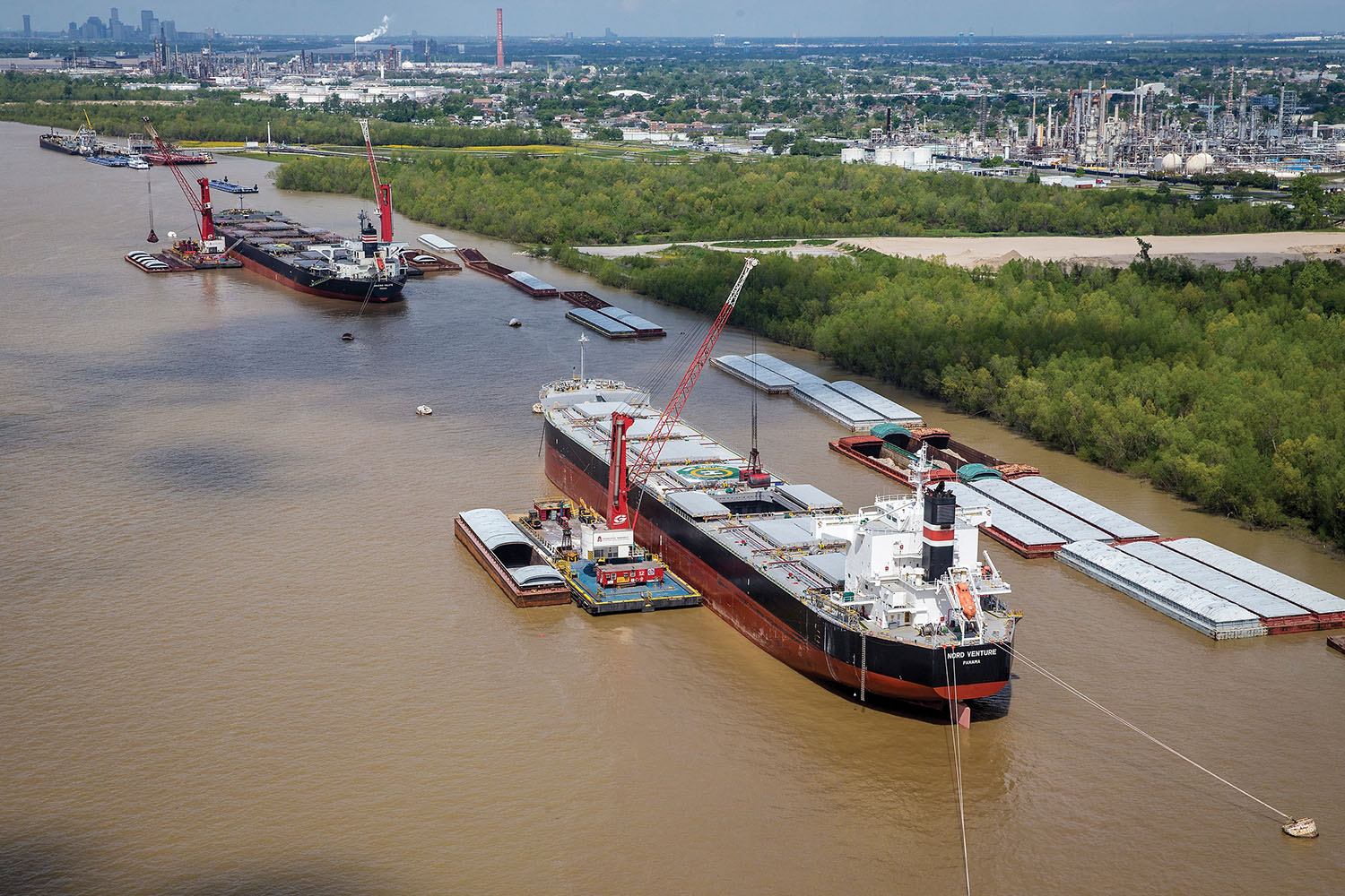 A pair of Associated Terminal’s floating Gottwald cranes transfer cargo between barge and ship near Violet, La., on the Mississippi River within the Port of St. Bernard. (Photo courtesy of Associated Terminals)