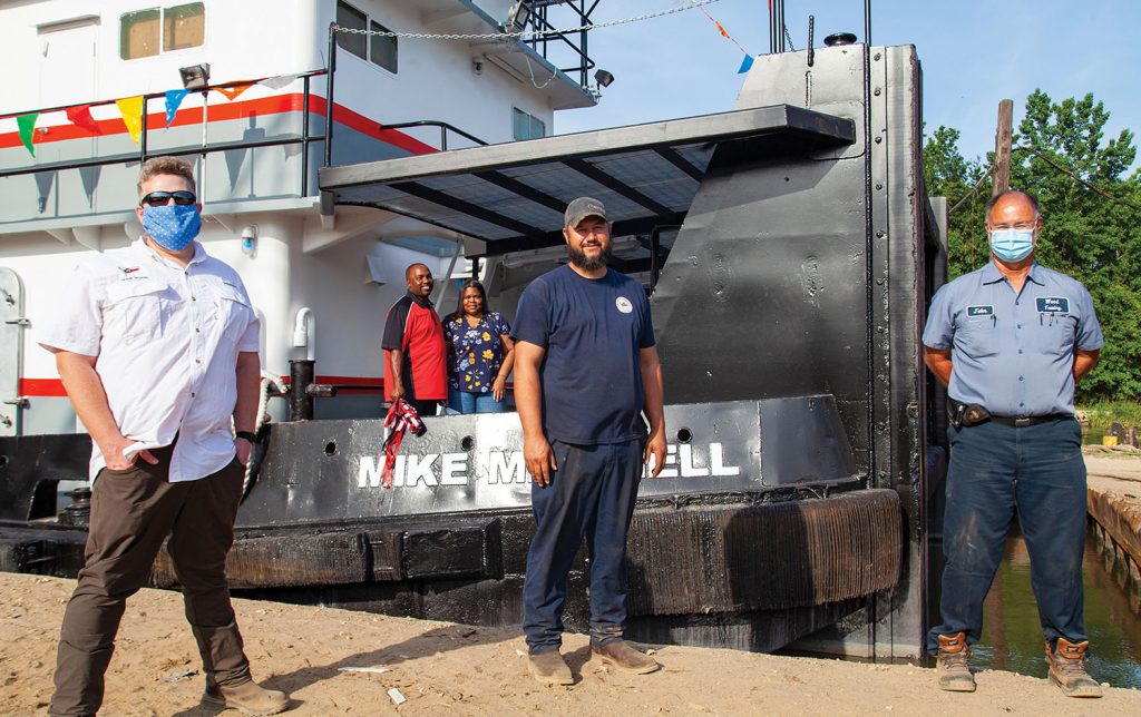 Mike and Natasha Mitchell stand aboard the mv. Mike Mitchell, along with (from left) Patrick McNeill, Wood Towing general manager, port engineer Jerry Bruce and operations manager John Madere. (Photo by Frank McCormack)