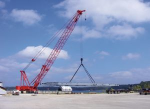 —photo courtesy of Yellow Creek Port A crane at the Yellow Creek State Inland Port loads bulkheads fabricated at G&G Steel onto a barge near the upper end of the Tenn-Tom.