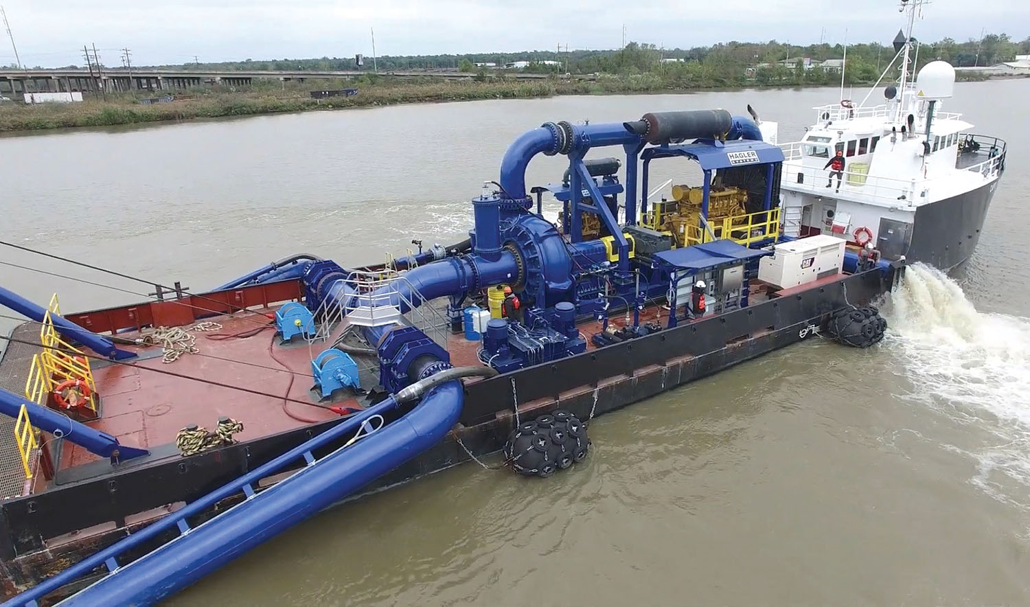 The vessel Captain John Graham tows the dredge Arulaq. The blue piping that is visible represents most of the dredge works. The fine silt sprays on the equipment, which means the deckhands are almost always constantly swabbing the dredge. (Photo courtesy of Brice Civil Contractors)