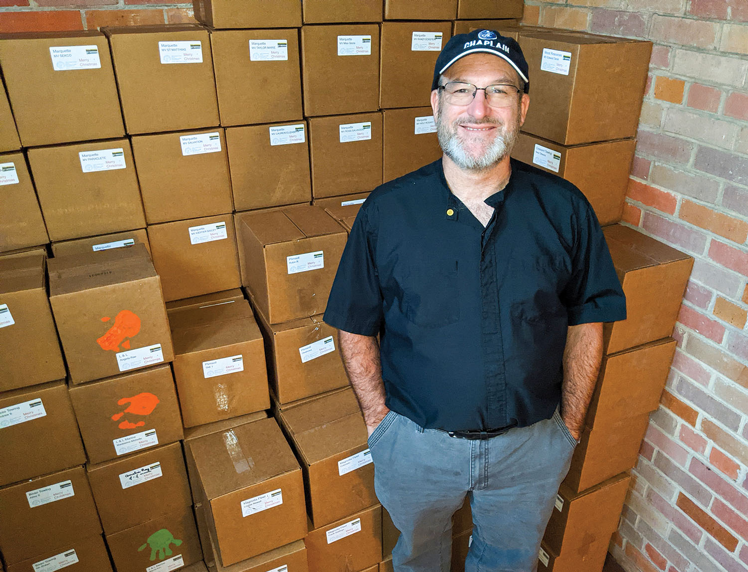 Rev. Tom Rhoades, Gulf region maritime and river chaplain for Seamen’s Church Institute, stands with a cache of Christmas At Sea boxes bound for towboats in south Louisiana. (Photo by Frank McCormack)