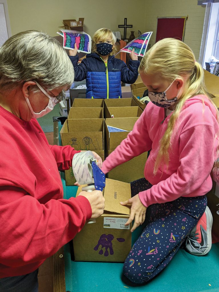 Joy Manthey, longtime towboat captain and chaplain, packs Christmas At Sea gift boxes with Ana and Julian McCormack. Photo by Frank McCormack)