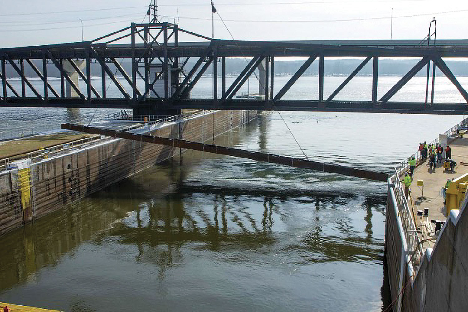 Personnel from the U.S. Army Engineer Research and Development Center and U.S. Geological Survey watch as a 350-ton crane lowers the 105-foot-long underwater Acoustic Deterrent System into the lock approach of Lock 19 near Keokuk, Iowa, February 3. (U.S. Army Corps of Engineers photo)