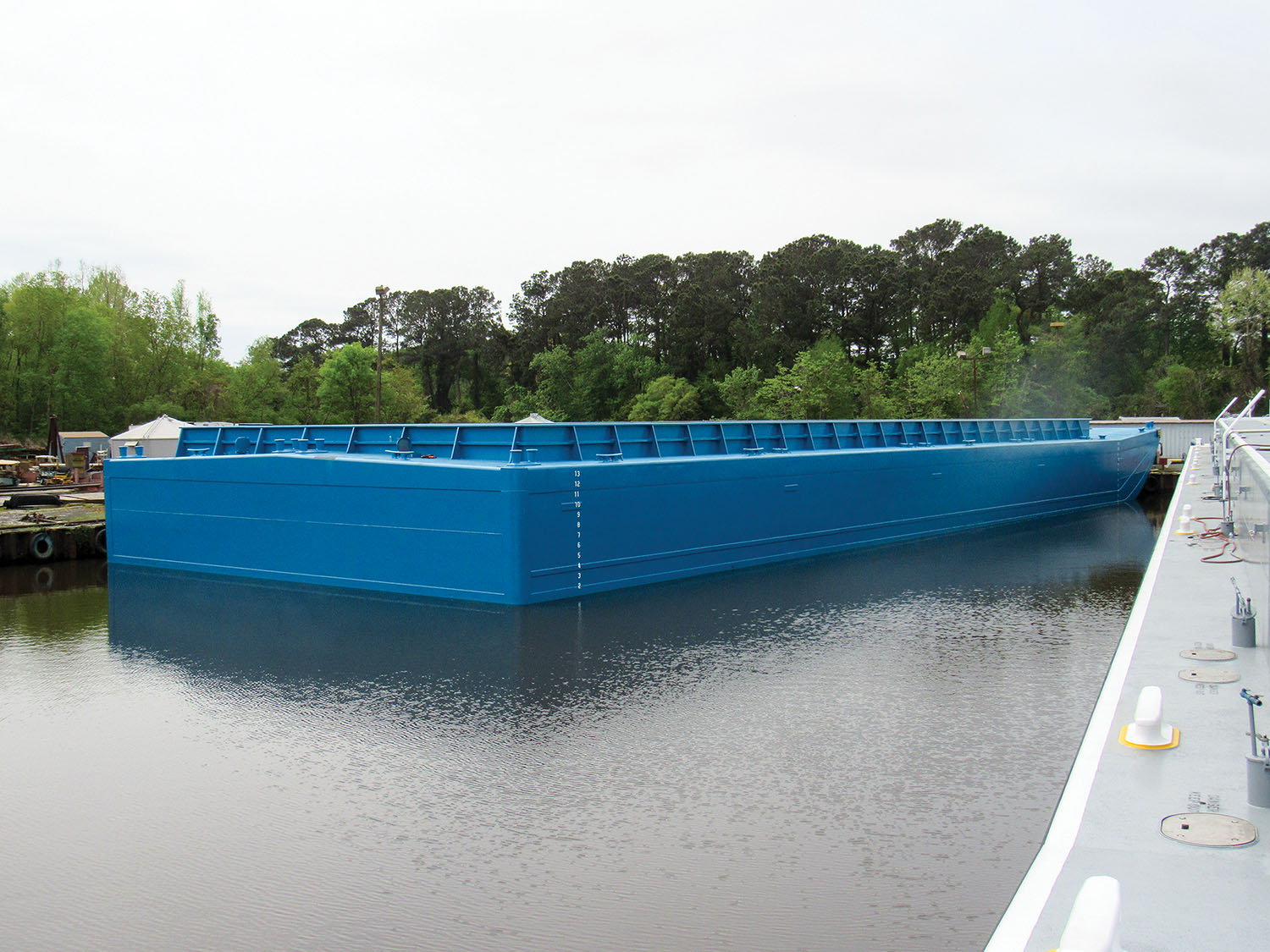 At 200 by 70 feet, the new barge takes up the same space in a tow as two standard hopper barges, but can hold 72 40-foot containers, nearly twice as much as the two standard barges would be able to handle.