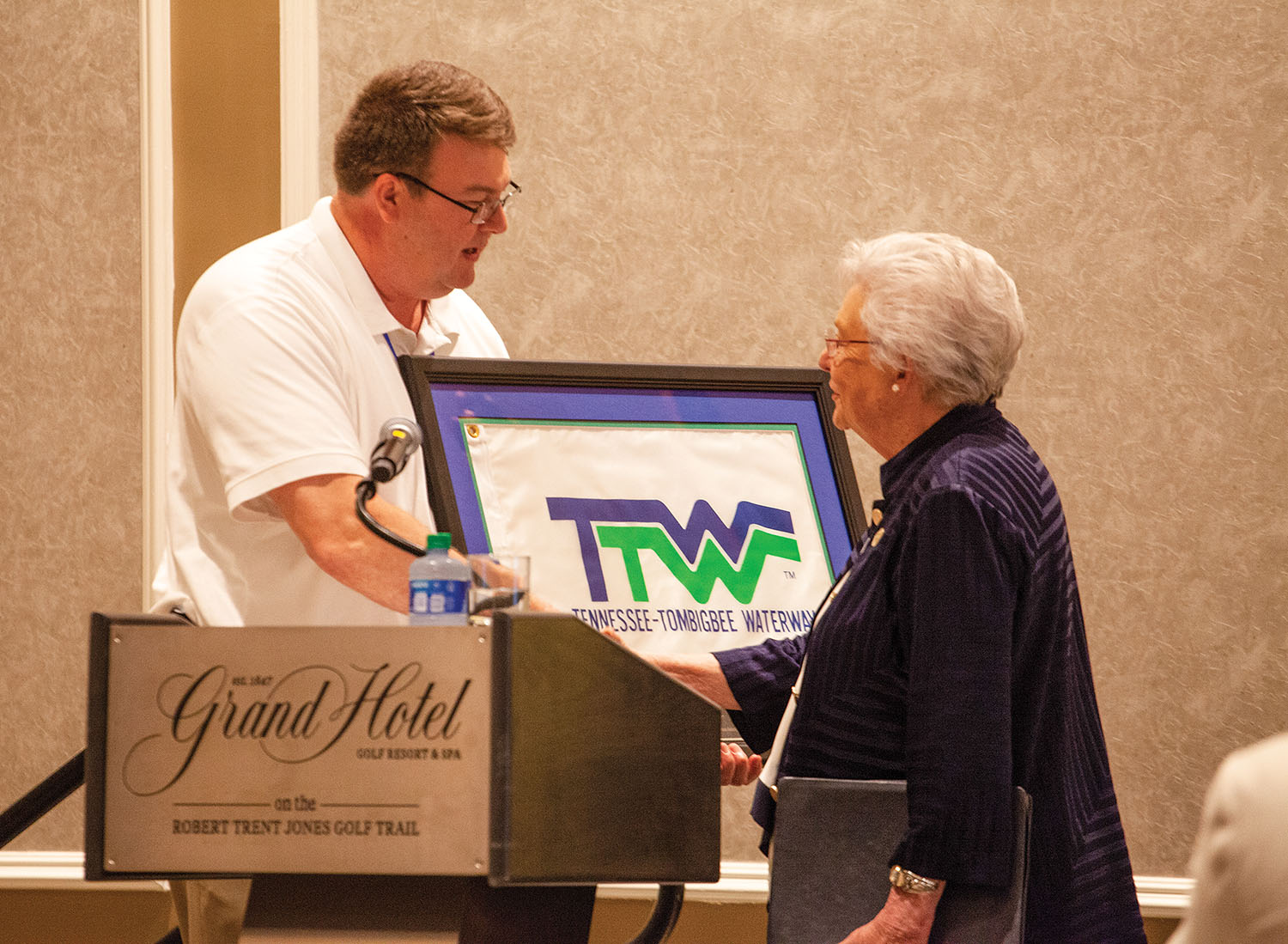 Mitch Mays, administrator of the Tennessee-Tombigbee Waterway Development Authority and president of the Tennessee-Tombigbee Waterway Development Council, presents Alabama Gov. Kay Ivey with a commemorative flag from the waterway’s official opening in the 1980s. (Photo by Frank McCormack)