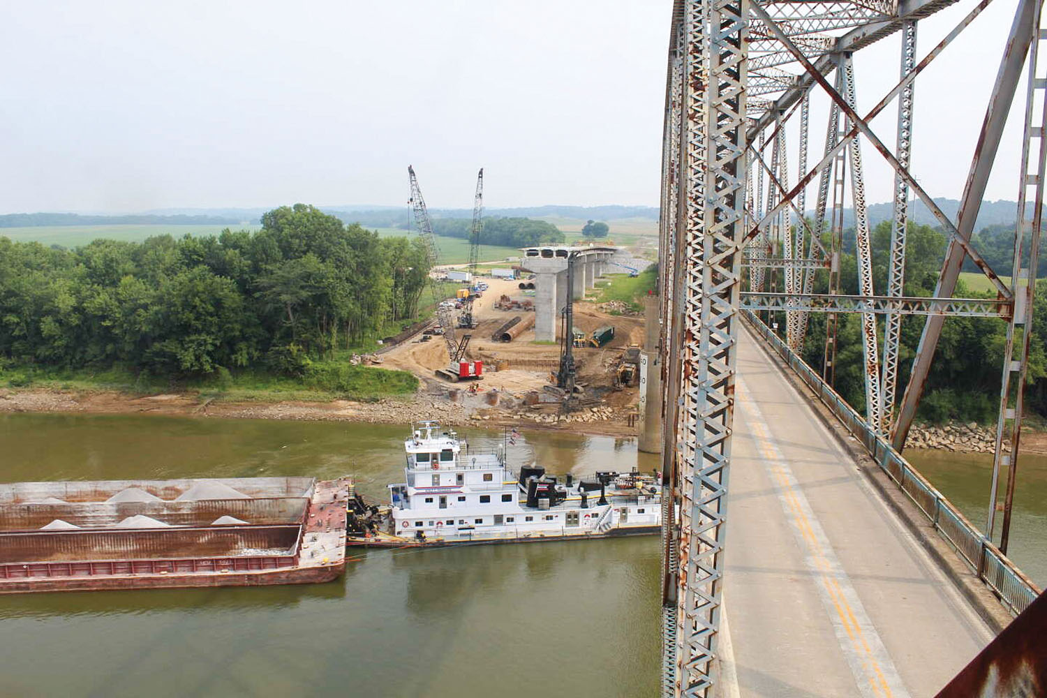 A towboat pushing a load of gravel passes beneath the current bridge over the river, built in 1931. The old bridge will be demolished as part of the $63.6 million project. (Photo courtesy of Kentucky Transportation Cabinet)