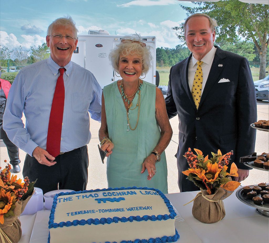 Kay Cochran is joined by Sen. Roger Wicker, left, and Mississippi State University President Mark Keenum to cut the cake at the lock renaming ceremony. (Photo courtesy of the Tennessee-Tombigbee Waterway Development Authority)