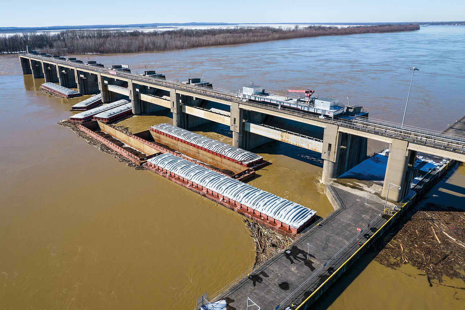 An 11-barge tow broke free in high water February 8 on the Ohio River as it was upbound coming out of Newburgh Locks and Dam. Four of the 11 barges eventually passed through the dam gates, with the others stuck along the top side of the dam. They were all recovered during salvage operations throughout the day, and navigation traffic resumed that evening. (Photo by 270 Drone Aerial Imagery)