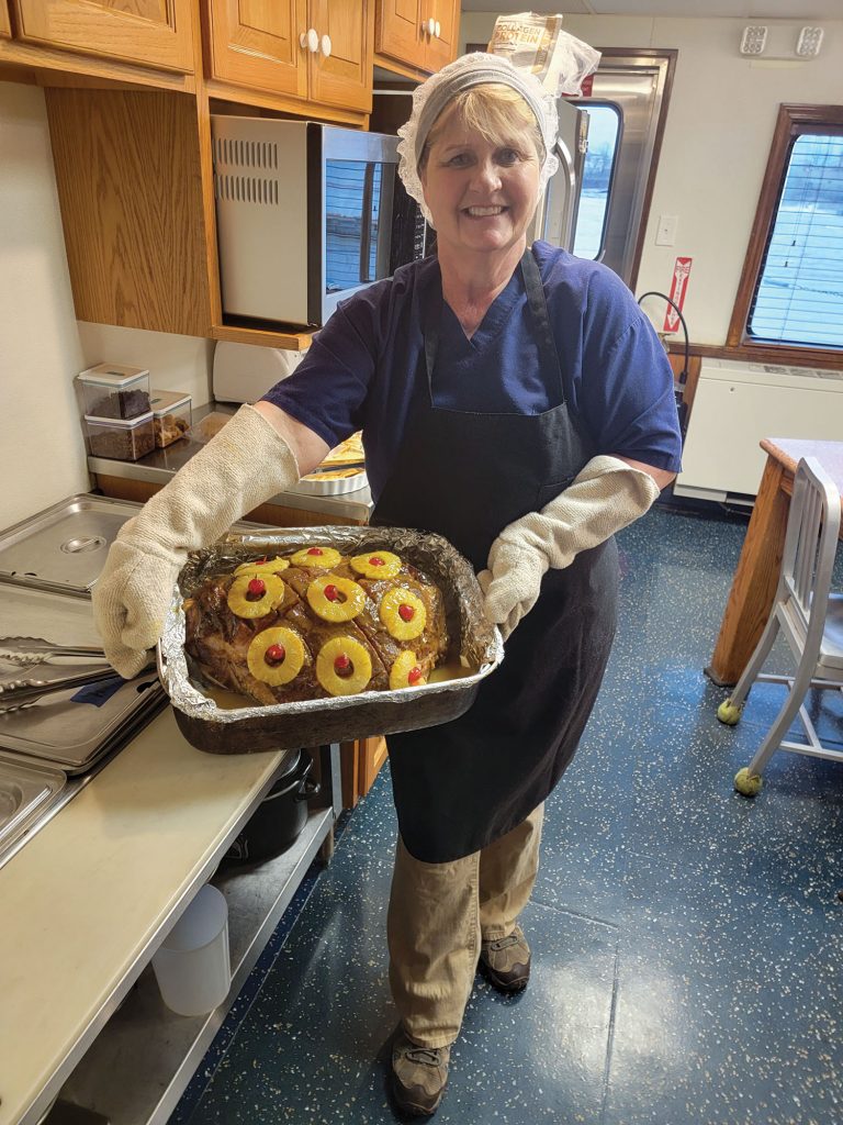 The author, in the galley of the Carl Page, with a ham with Stacie’s Ham Glaze.