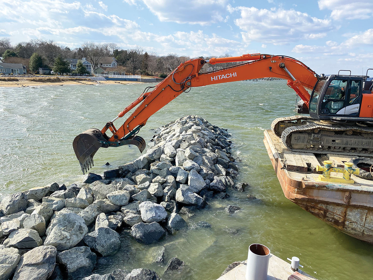 A Shoreline Design excavator places stone on the east breakwater in March 2021. The operator had to choose the best placement for each stone.