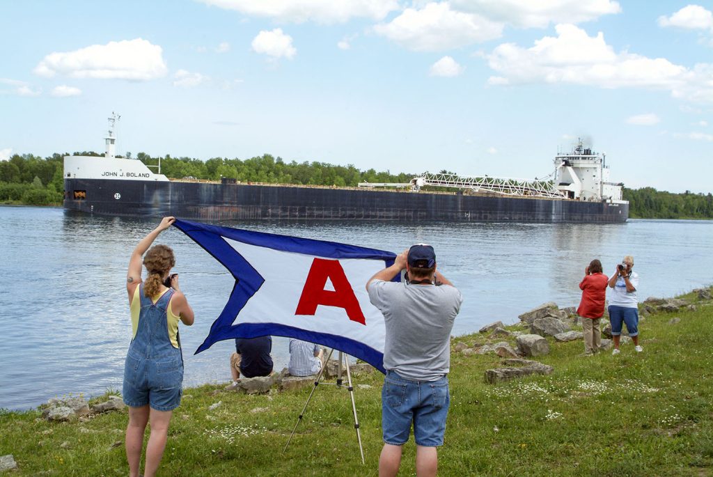 Boatnerds gather to greet an American Steamship Company ship with a company flag.