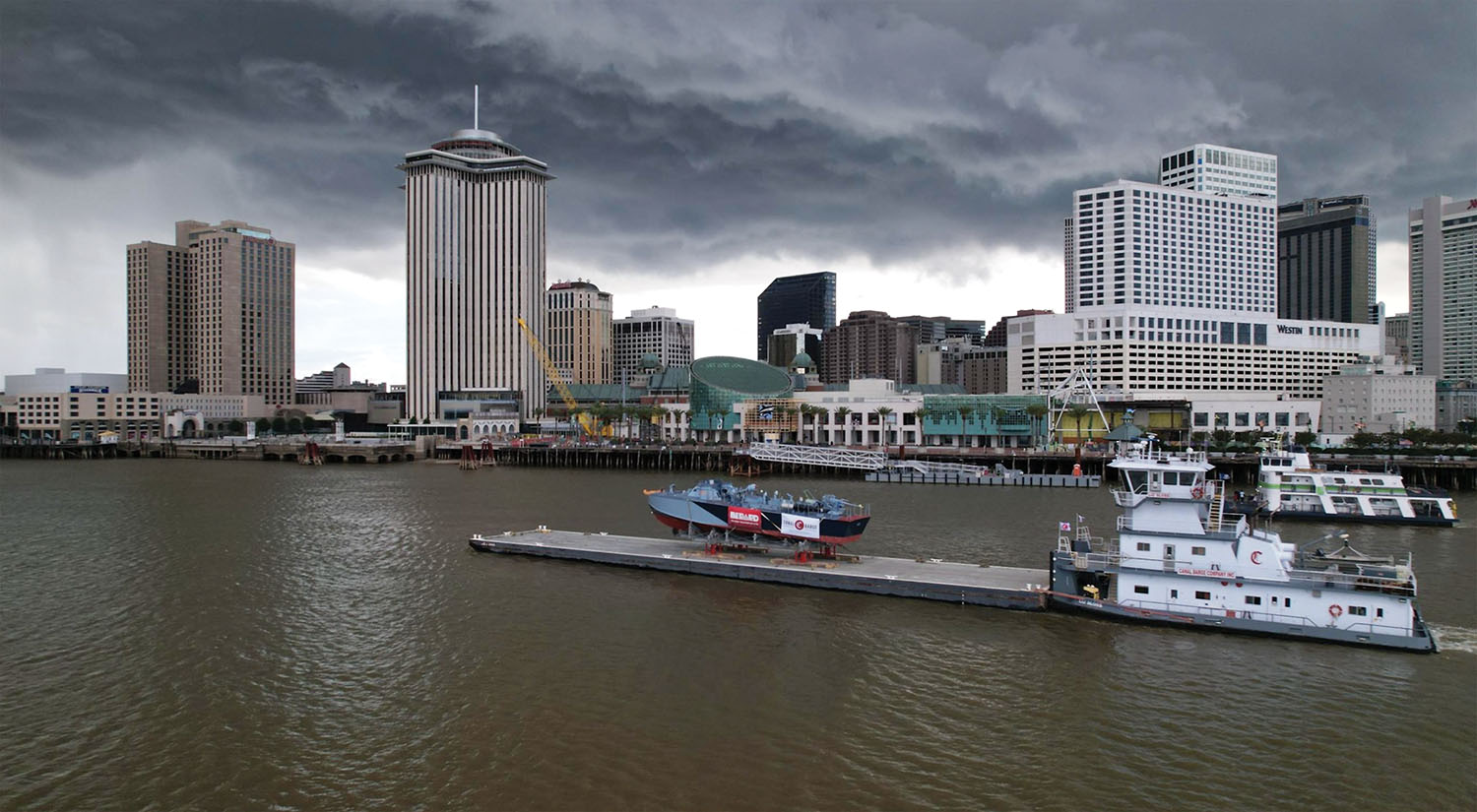 Canal Barge Company’s mv. Liz Sloss pushes a deck barge loaded with PT-305 up the Mississippi River in New Orleans July 7 en route to the Erato Street Cruise Terminal. (Photo courtesy of Canal Barge Company)