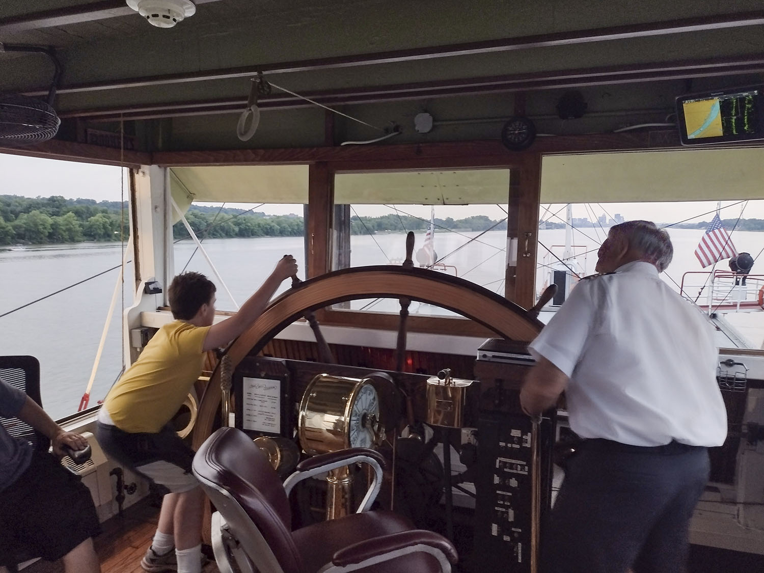 Drew Byrne, 12, strains as he turns the Belle of Louisville’s original wooden wheel while Capt. Mike Fitzgerald keeps a steady hand on the lever. (Photo by Shelley Byrne)