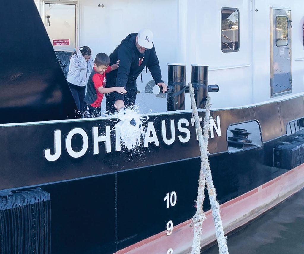 John Austin, 7-year-old son of Austin Sperry, christens his namesake vessel, with help from his father and sister, Genevieve. (Photo courtesy of Maritime Partners)