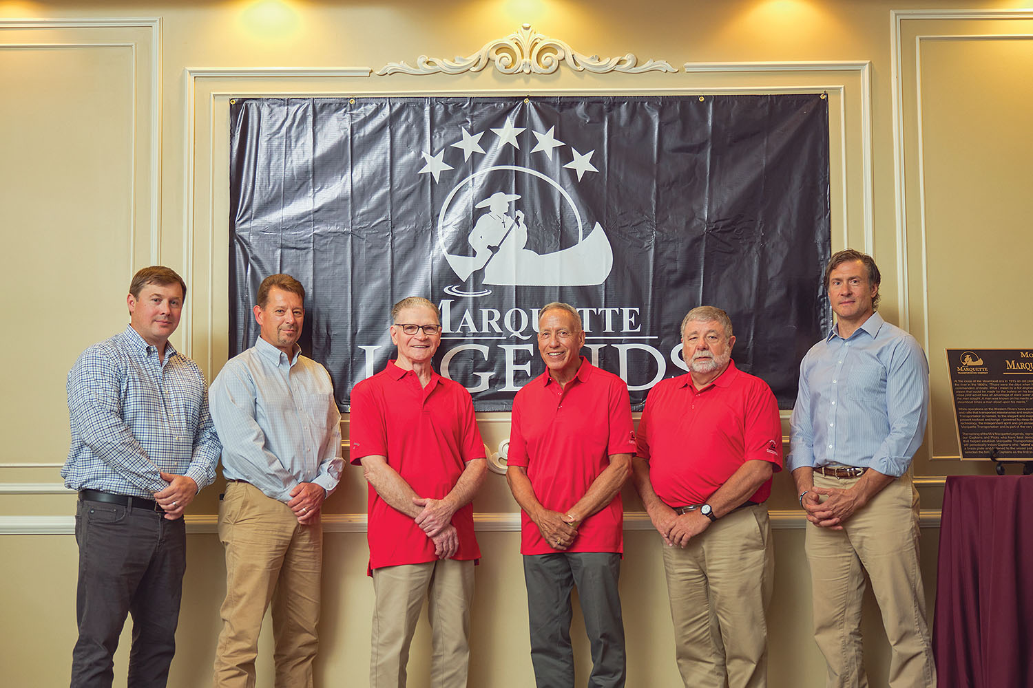 The 2022 class of Marquette Legends includes (in red shirts, from left): Capt. John Zeringue, Capt. Emile Dufrene and Capt. Dennis Drury. With them, from left, are Damon Judd, president and CEO of Marquette Transportation; Darin Adrian, executive vice president, river division; and Chris Myskowski, senior vice president of operations, river division. (Photo courtesy of Brad Rankin Studio)