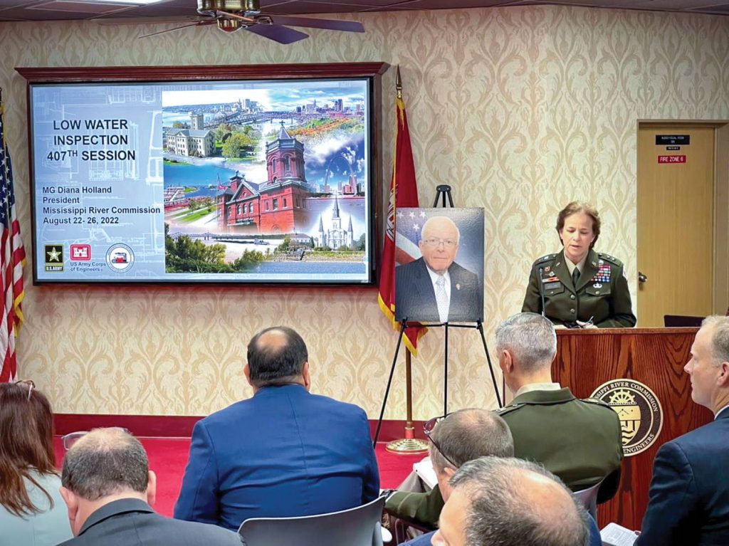 Maj. Gen. Diana Holland, commander of the Mississippi River Division and president of the Mississippi River Commission, speaks to those attending a commission meeting. Behind her is a photo of former Commissioner Sam E. Angel, who died earlier this month. He was the longest serving member of the commission with more than 40 years of service. (Photo by VI Specialist Vance Harris)