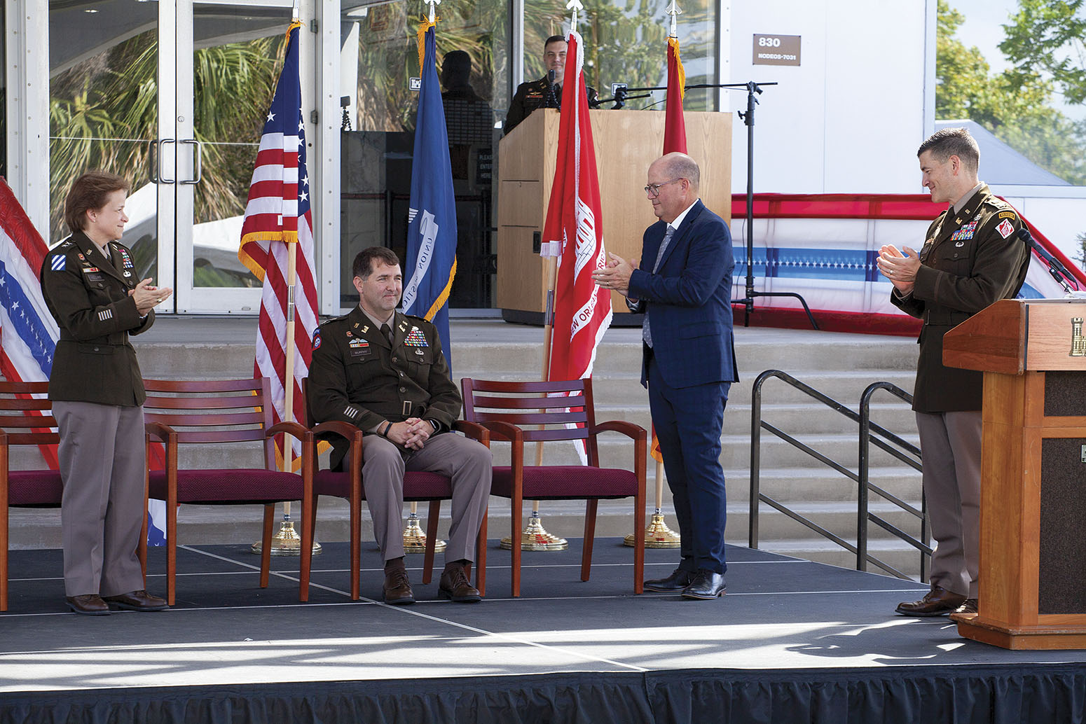 Mississippi Valley Division Commander Maj. Gen. Diana Holland, Mark Wingate, deputy district engineer for programs and project management, and new commander Col. Cullen Jones applaud outgoing district commander Col. Stephen Murphy, seated. (Photo by Frank McCormack)