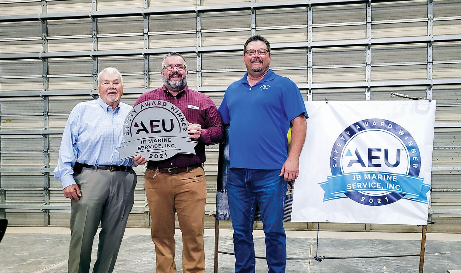 JB Marine officials George Foster, president (left), and Les Kapper, director of safety (right), receive the AEU Safety Award from David Widener, managing director of American Equity Underwriters.