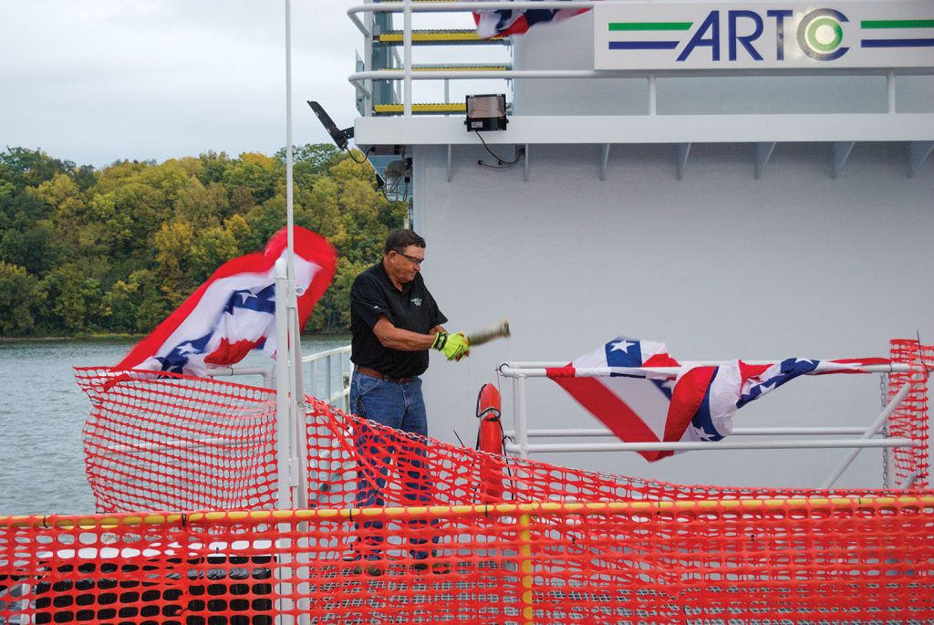 Chuck Burlingame, who worked for ADM for 46 years before retiring in 2021, breaks a bottle over the railing of his namesake vessel, the Chuck B. (Photo courtesy of ARTCo)