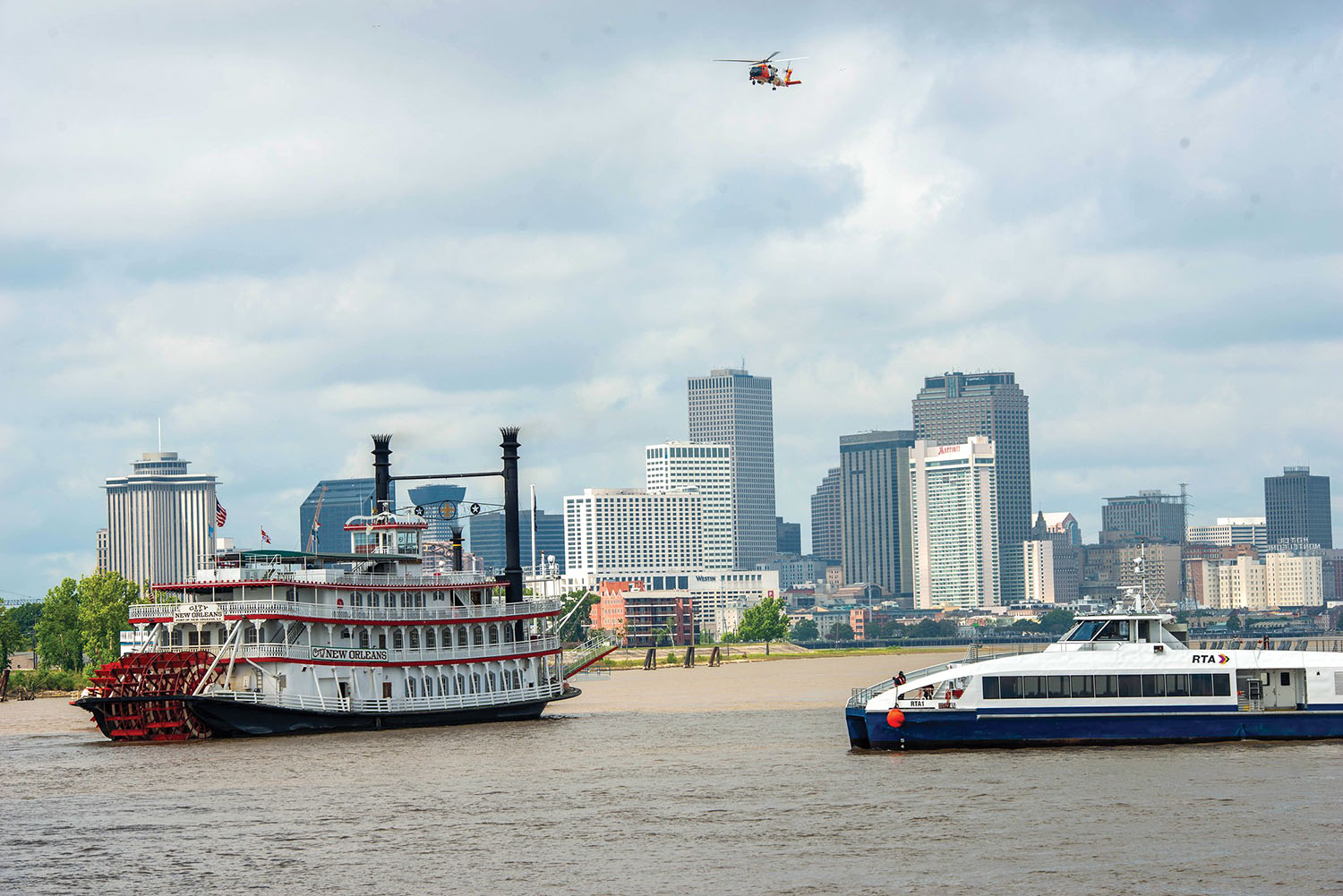 The City of New Orleans, a New Orleans RTA ferry and a Coast Guard helicopter take part in a rescue exercise on the Mississippi River April 26. (U.S. Coast Guard photo)