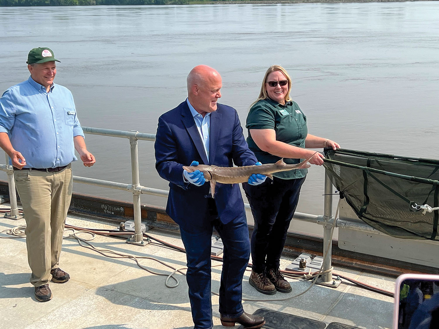 U.S. Infrastructure Coordinator Mitch Landrieu prepares to release a freshly tagged lake sturgeon into the river at Lock 22. (Photo by Paul Rohde)