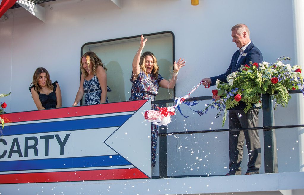 Jill McCarty breaks a bottle of champagne over the railing to dedicate the mv. Rich McCarty.