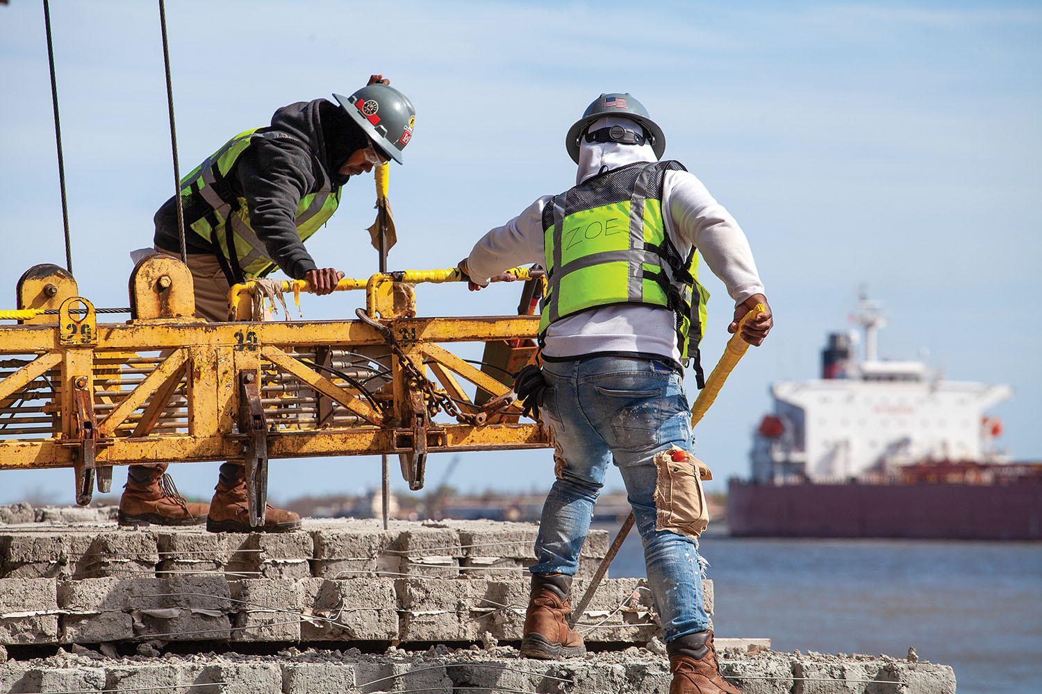 Two Mat Sinking Unit crew members work aboard the unit’s cement barge just below Neptune Pass near Triumph, La., as the crude oil tanker Xanthos passes by. (Photo by Frank McCormack)